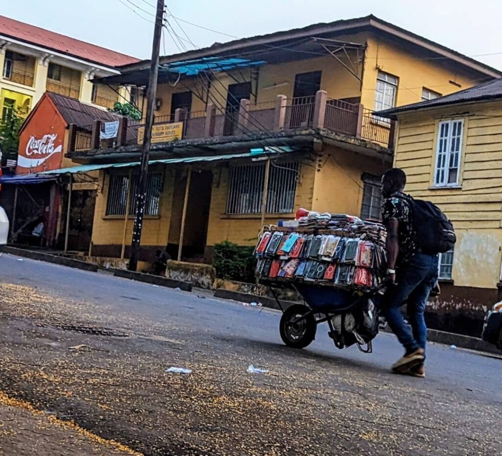 A man hawking mobile phones accessories on a cart. Photo: Engage Salone